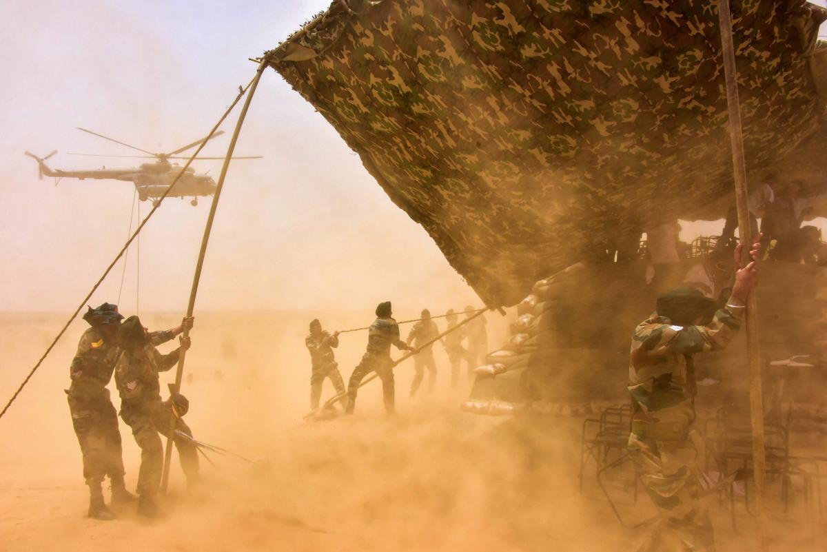 Army personnel try to control scaffolding structure as a chopper blows sand during the ongoing military exercise Vijay Prahar, in Bikaner on Wednesday. PTI