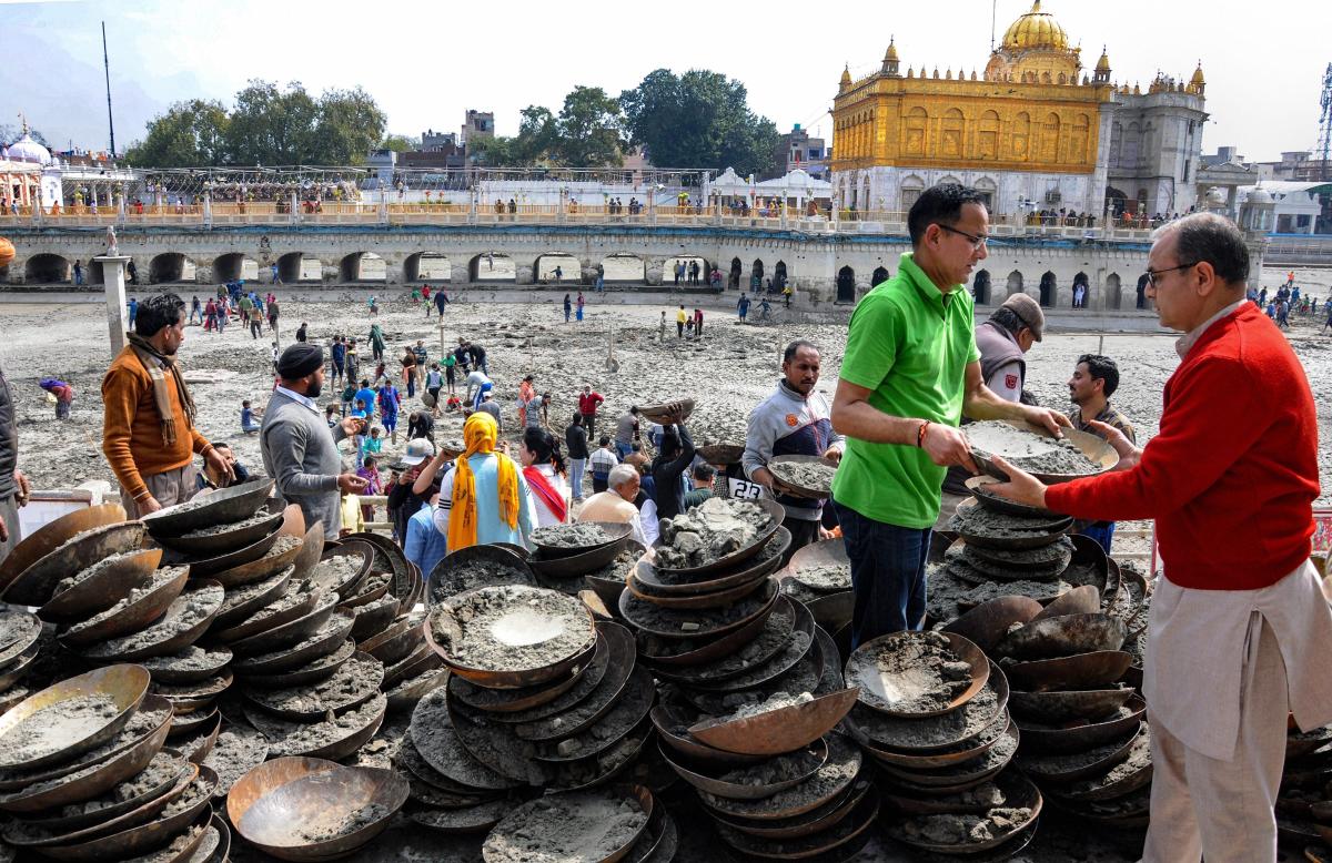 Devotees perform 'Kar Sewa' (voluntary service) of cleaning the holy pond of Durgiana Mandir, in Amritsar. PTI