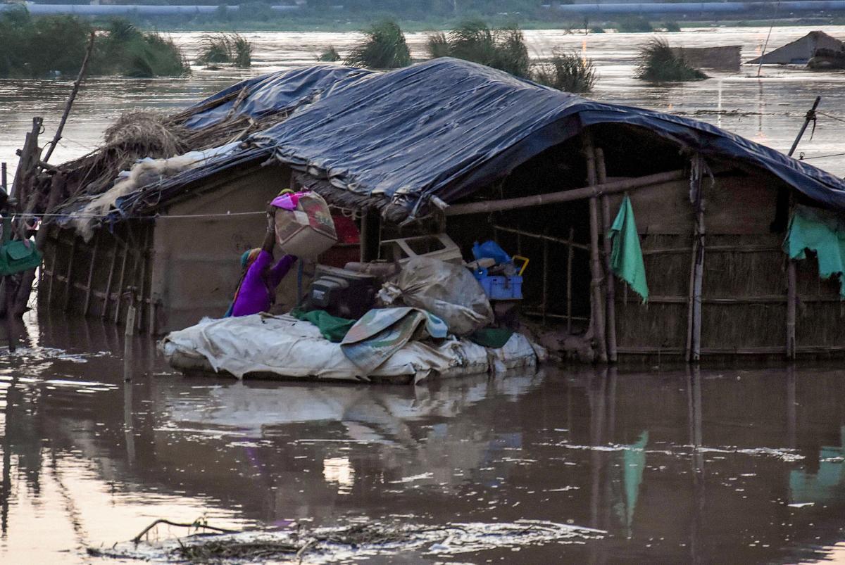A woman transfers her belongings to a makeshift raft in the swollen Yamuna river following the release of water from Hathni Kund barrage near Nigam Bodh ghat in New Delhi, Tuesday, Aug 20, 2019. (PTI Photo)