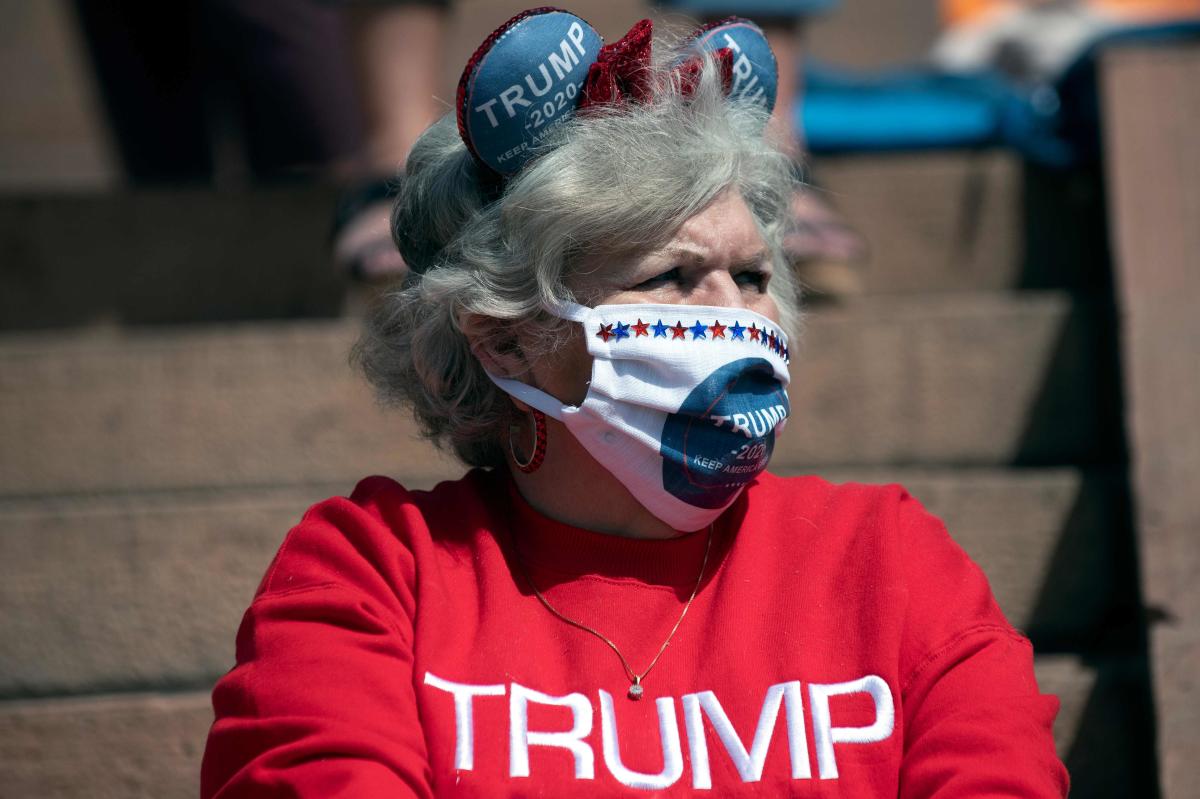 A demonstrator wearing a Trump 2020 face mask gathers with others to protest coronavirus stay-at-home orders during a