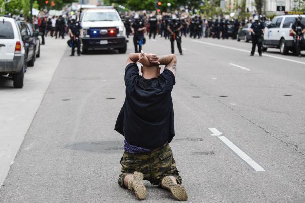 A man sits on his knees in front of police officers by the Colorado State Capitol as protests against the death of George Floyd continue for a third night on May 30, 2020 in Denver, Colorado. The city of Denver enacted a curfew for Saturday and Sunday nights and Governor Jared Polis activated the Colorado National Guard in hopes of stopping protests that have wreaked havoc across the city. Michael Ciaglo/Getty Images/AFP