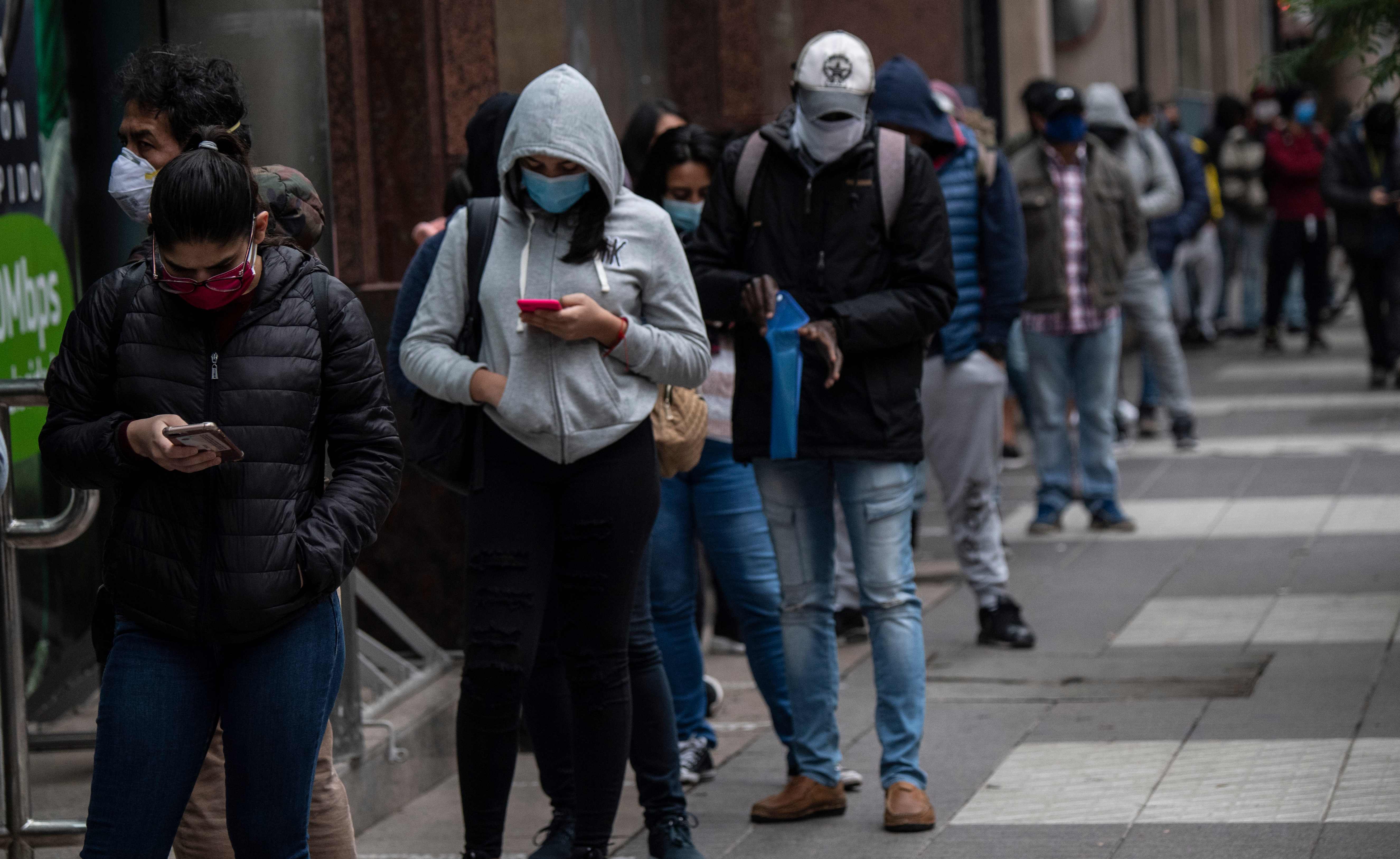 People wear face masks as they queue to get an unemployment insurance outside the Chilean Unemployment Funds Administration headquarters in Santiago. Credits: AFP Photo