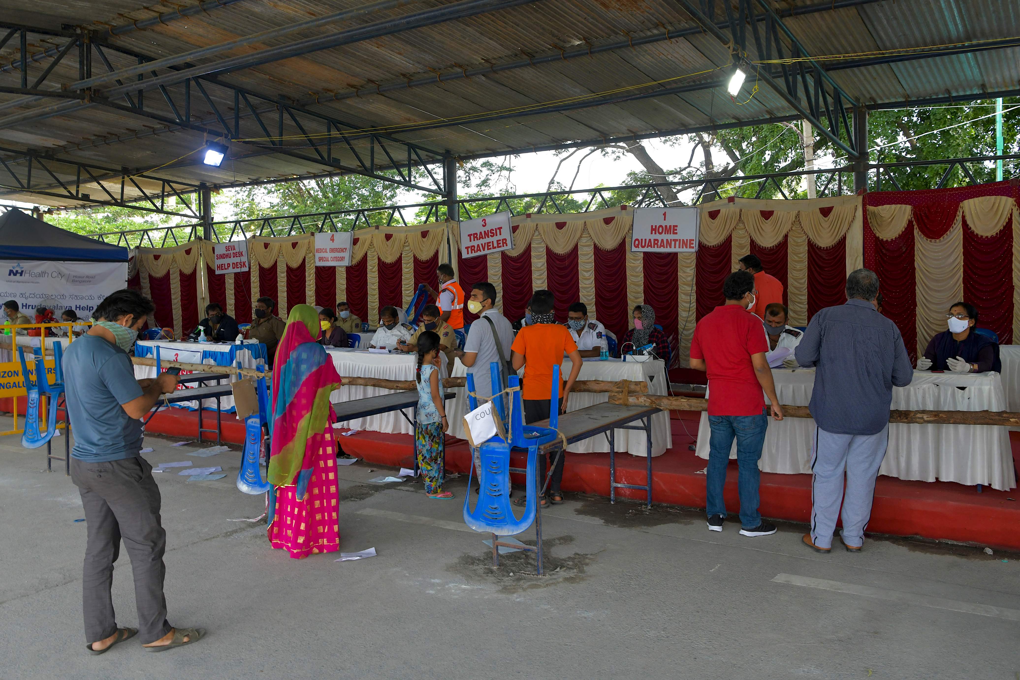 People arriving to Bangalore from Tamil Nadu line-up to undergo a health screening and scrutiny at a check post. Credit: AFP Photo