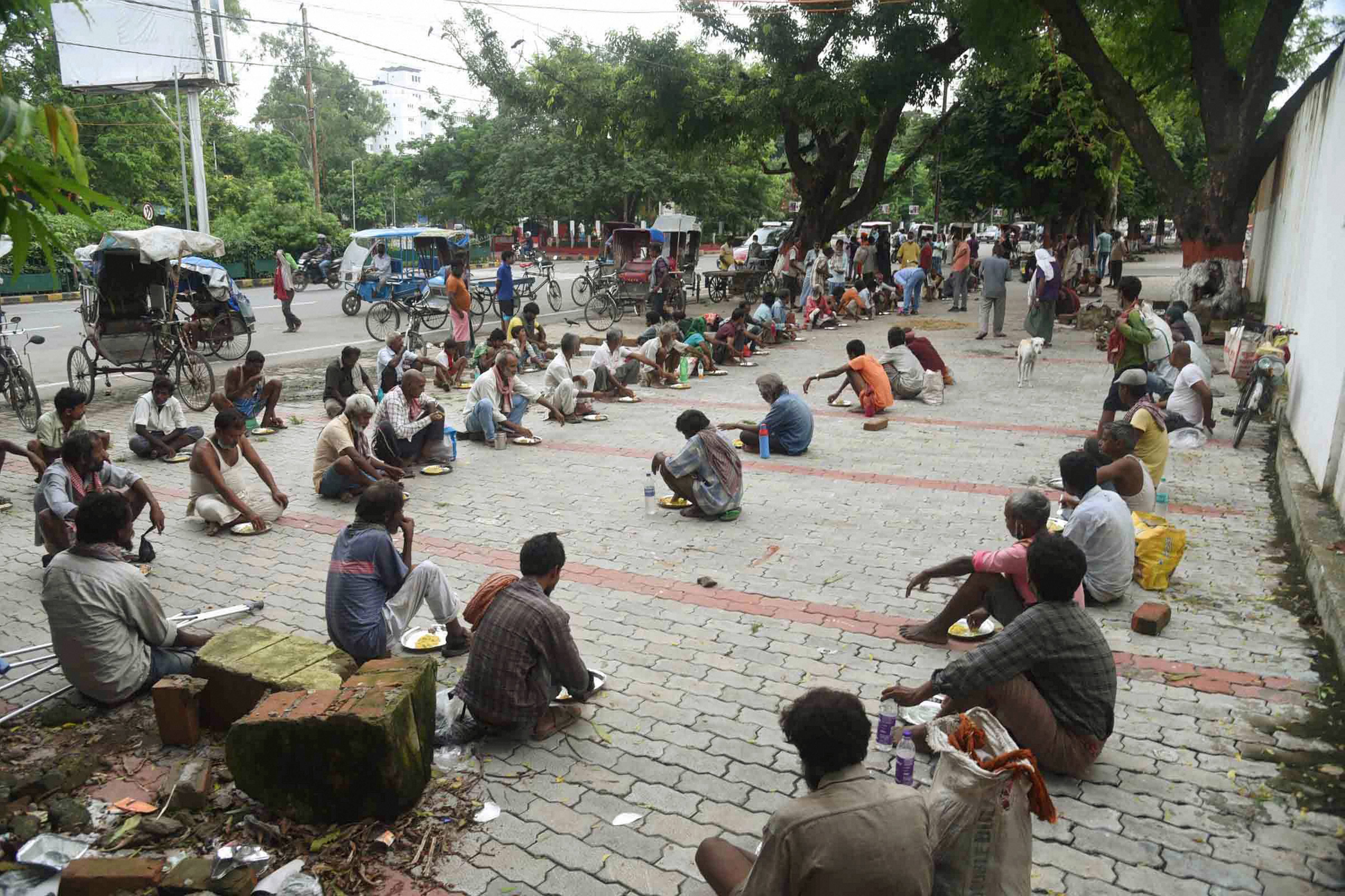 Homeless and the needy consume meals distributed by volunteers, amid a total lockdown in the area to curb the spread of coronavirus disease, in Patna. Credit: PTI Photo