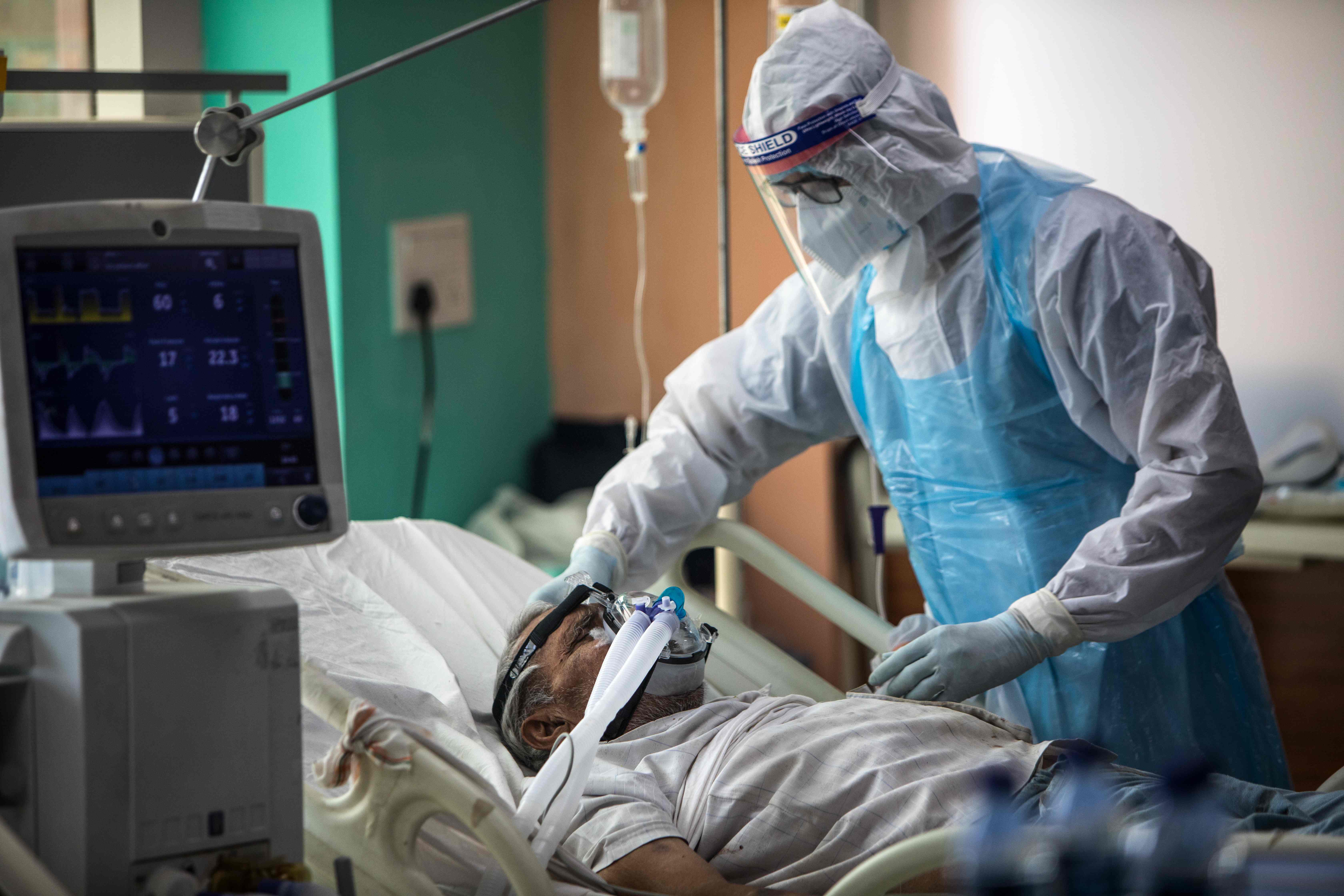 A medical staff wearing Personal Protective Equipment (PPE) suit looks after a COVID-19 coronavirus patient at the Intensive Care Unit of the Sharda Hospital, in Noida. Credits: AFP Photo