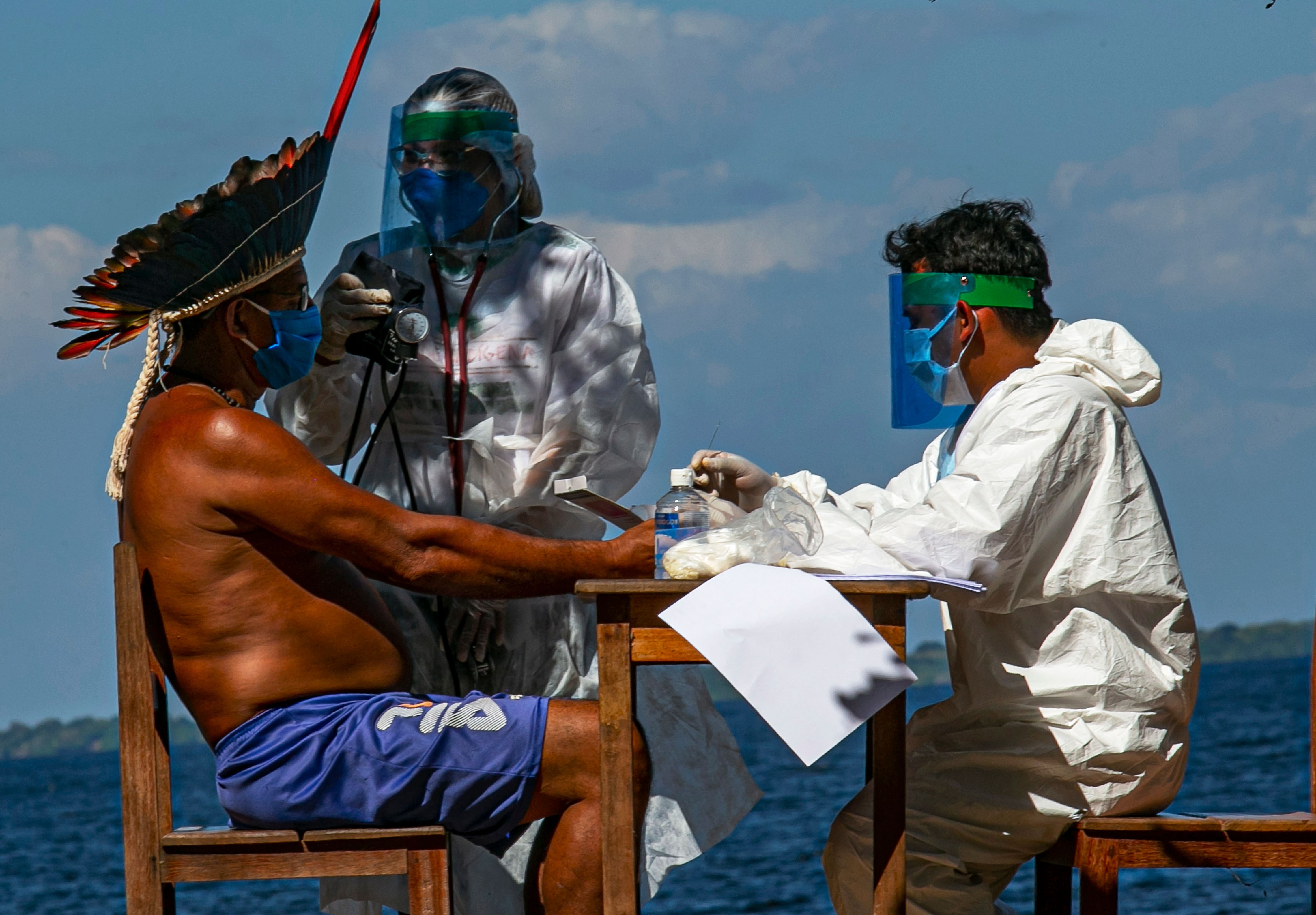 Indigenous nurses from the Special Secretariat for Indigenous Health (Sesai) of the Arapiuns ethnic group and Tapuia ethnic groups perform a rapid COVID-19 test on Chief Domingos from the Arapium tribe on the banks of the lower Tapajos River in the municipality of Santarem in western Para on July 19, 2020. Credit: AFP)