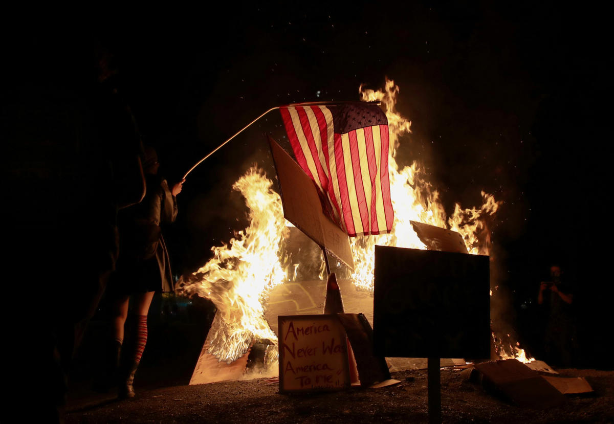 A demonstrator sets fire to an American flag during a protest against racial inequality and police violence in Portland, Oregon, US. Credit: Reuters Photo
