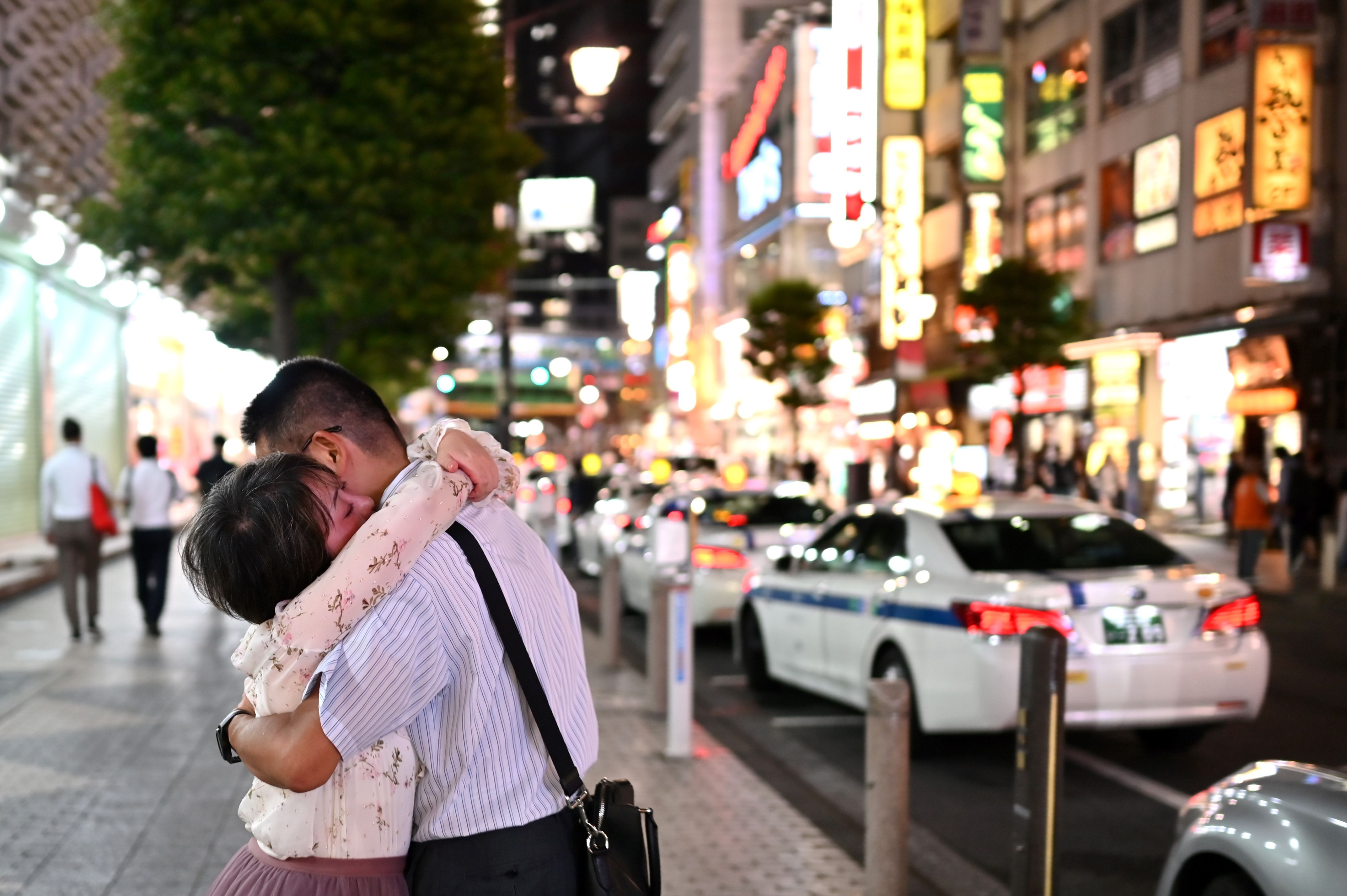 A couple hug each other by a street in Tokyo on September 2, 2020. Credit: AFP Photo