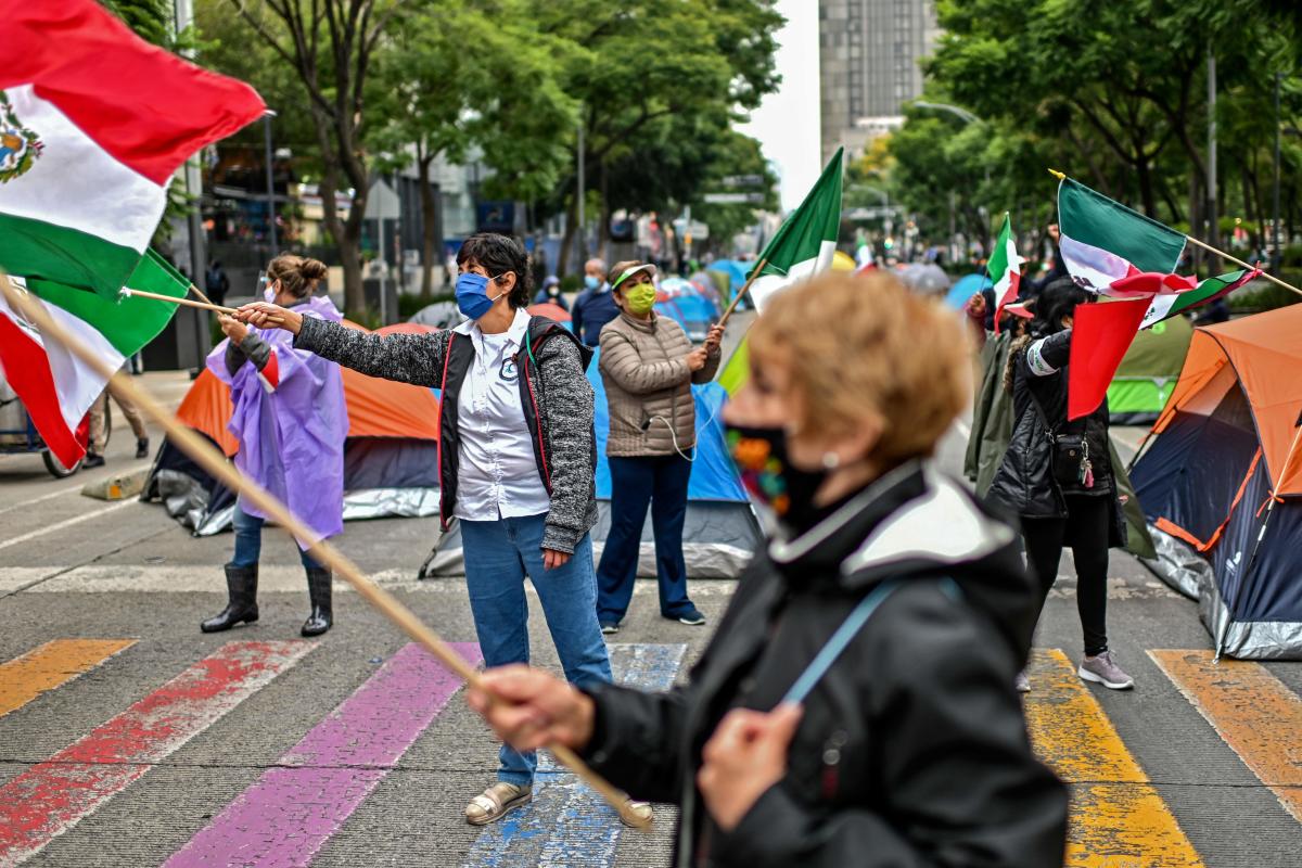 Members of the National Front Anti-AMLO (Frena), who will make a second attempt to reach Zocalo Square to protest against Mexican President Andres Manuel Lopez Obrador (ALMO), flutter Mexican flags as they camp on Juarez street in Mexico City, a day after being prevented by the local police to get to the city's main square, amid the Covid-19 pandemic. Credit: AFP Photo