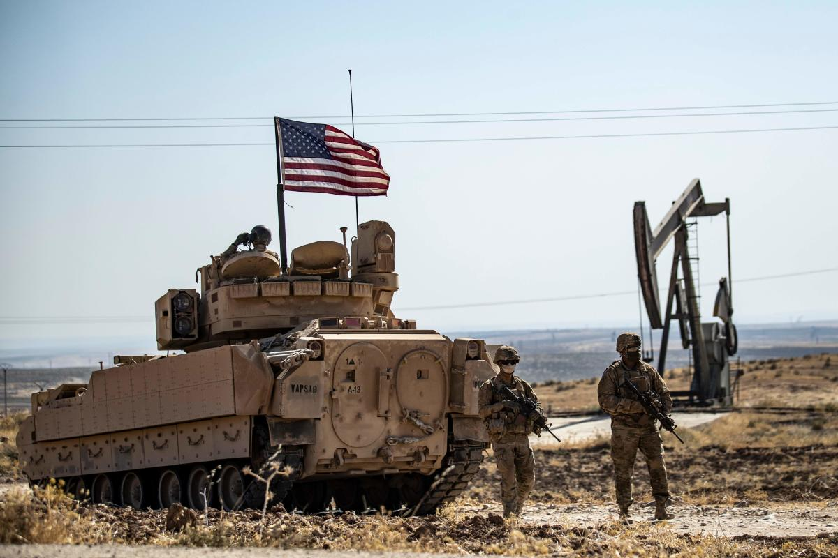 US soldiers walk near a Bradley Fighting Vehicle (BFV) during a military patrol in the countryside near al-Malikiyah (Derik) in Syria's northeastern Hasakah. Credit: AFP Photo