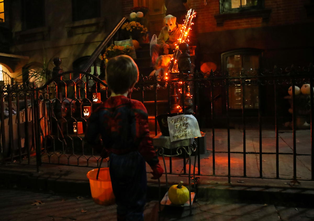 Felix Hassebroek looks at a sign posted while trick-or-treating with his family during the outbreak of coronavirus disease in Brooklyn, New York, US. Credit: Reuters Photo