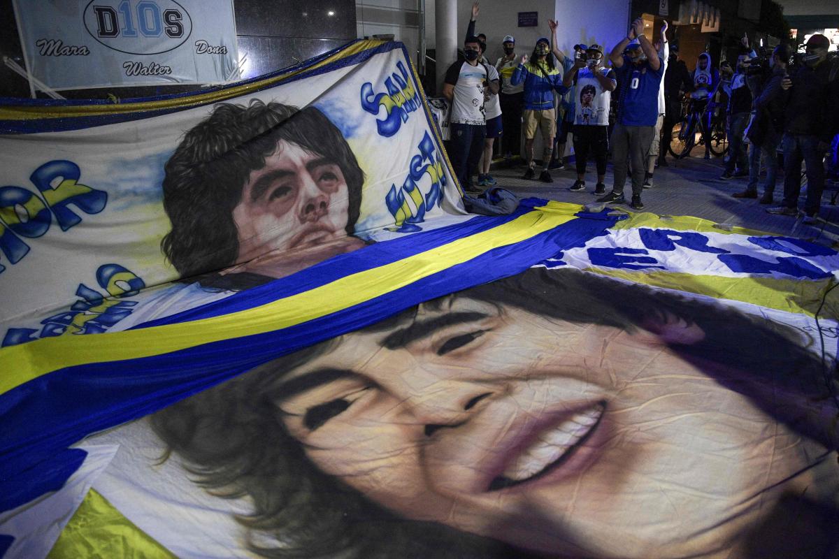 Supporters of Argentine former football star and coach of Gimnasia y Esgrima La Plata Diego Maradona gather outside the hospital where he undergoes a brain surgery for a blood clot, in Olivos, Buenos Aires. Credit: AFP Photo