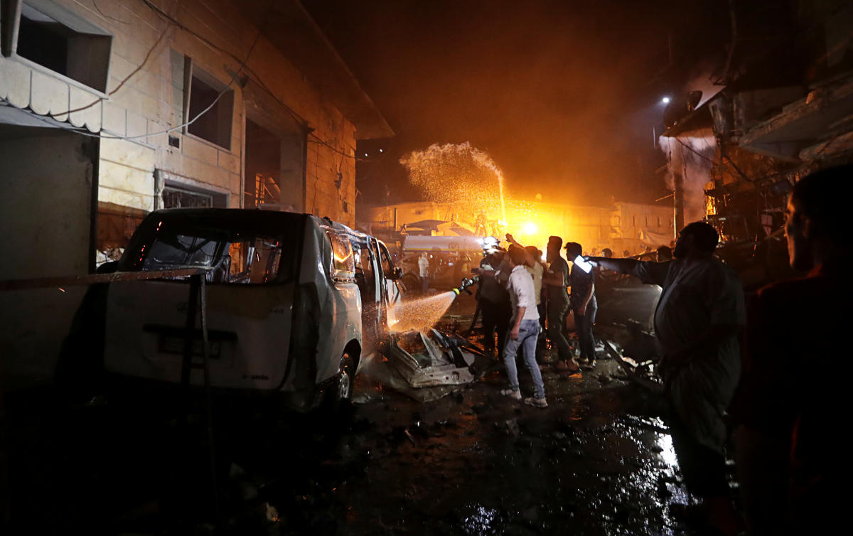 4. Syria | People try to extinguish a fire at the site of a car bomb blast in Azaz, Syria. Credit: Reuters Photo