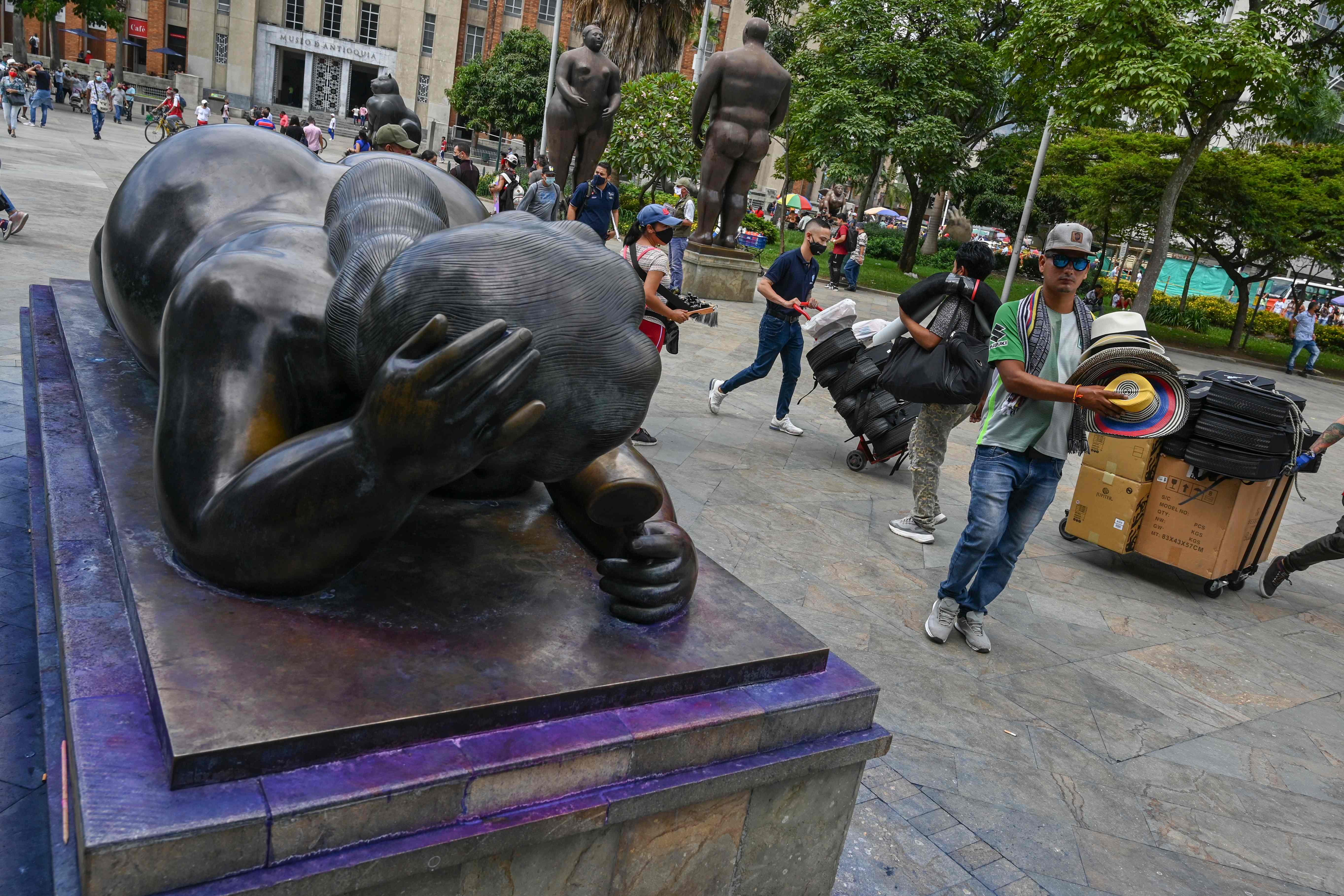 People are pictured near a sculpture by the Colombian artist Fernando Botero which was vandalized and then washed away unsuccessfully by authorities in Medellin, Colombia. Credit: AFP