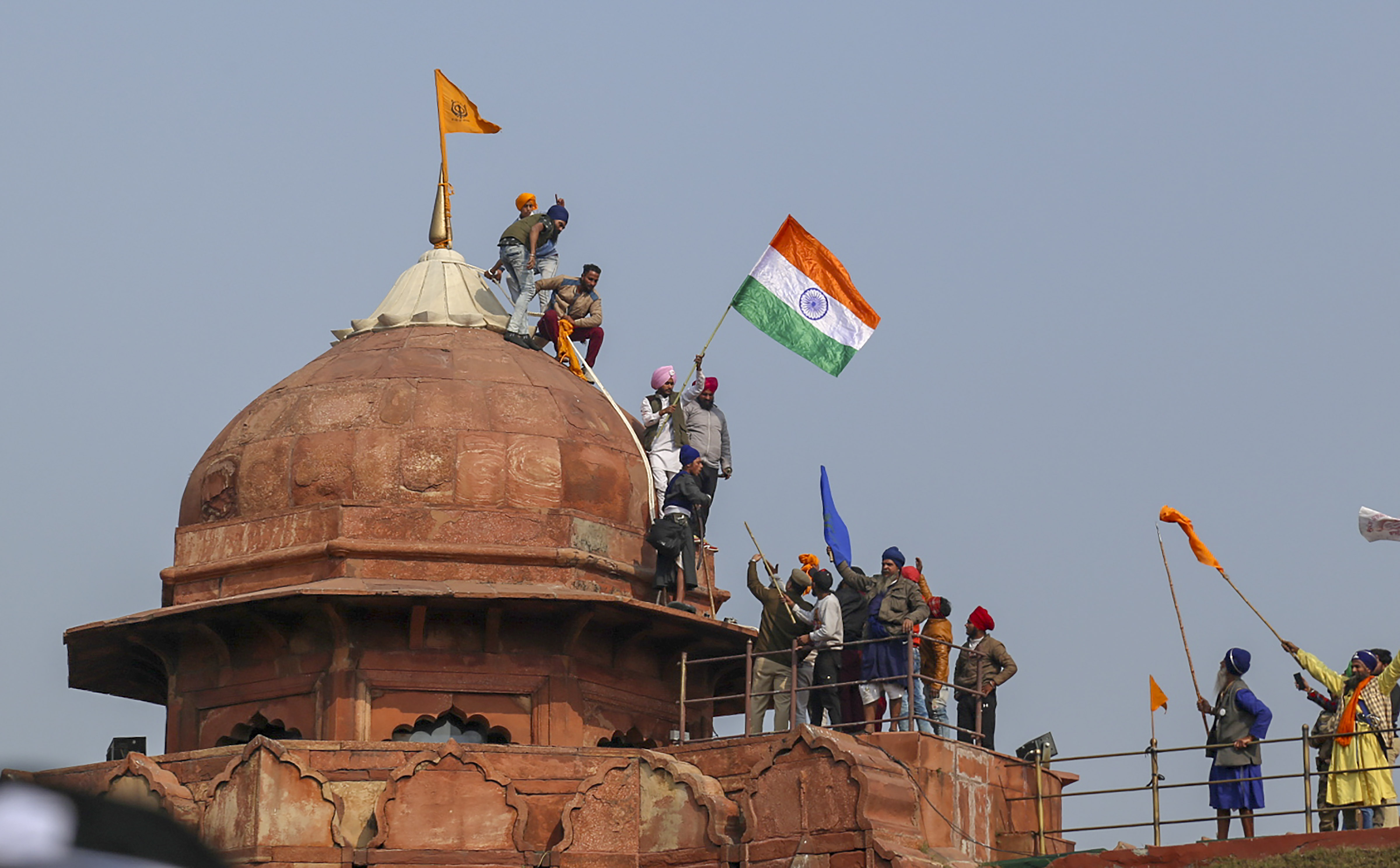 The saffron flag hoisted by protesters from the staff at the iconic Red Fort during their tractor parade against the farm laws on Tuesday was the 'Nishan Sahib', a symbol of Sikh religion seen at all Gurdwara complexes.  The 'Nishan Sahib' is a triangular flag that is sacred to Sikhs. The emblem on the flag comprises of 'Khanda', a two-edged sword, Chakra, a disc, and two Kirpans that cross each other at the handles. The other flag appeared to be of a farmer union. Credit: PTI