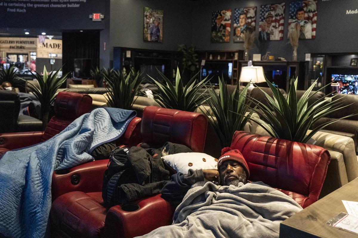 Michael Kirkland, 57, rests on a chair while taking shelter at Gallery Furniture store which opened its door and transformed into a warming station. Credit: AFP photo.