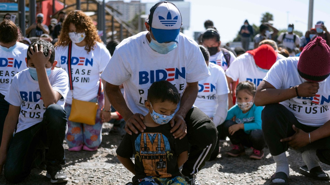 Yadiel Garcia and his father Fabricio, from Honduras, kneel as they pray during a migrant demonstration demanding clearer United States migration policies, at San Ysidro crossing port in Tijuana, Baja California state, Mexico. Credit: AFP Photo