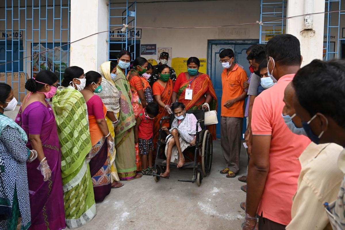 An elderly voter is assisted by an election official after casting her vote at a polling station during Phase 2 of West Bengal's legislative election in Nandigram. Credit: AFP Photo