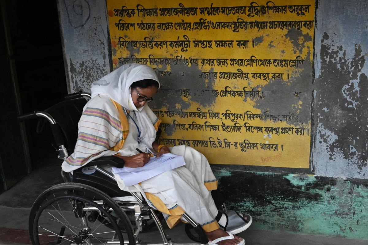 West Bengal's Chief Minister Mamata Banerjee takes notes while sitting in a wheelchair at a polling station during Phase 2 of West Bengal's legislative election in Nandigram. Credit: AFP Photo