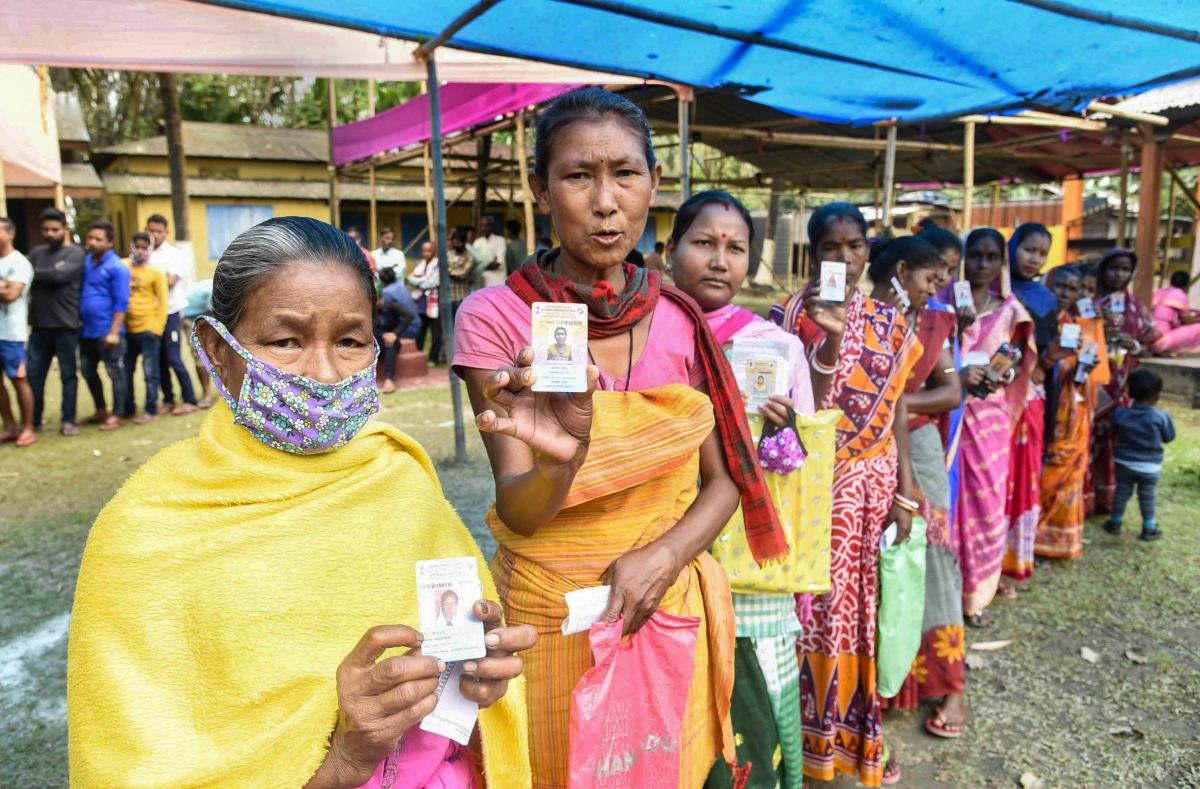 Tribal women wait to cast their votes during the second phase of Assam Assembly polls, in Morigaon. Credit: PTI Photo