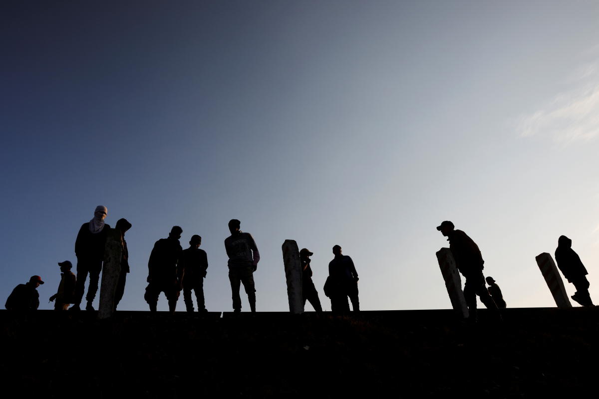 Central American migrants stand on the train track outside the