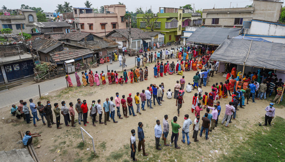 People stand in a queue to cast their vote at a polling station during the 6th phase of State Assembly Election at Birati, in North 24 Parganas, Thursday, April 22, 2021. Credit: PTI Photo