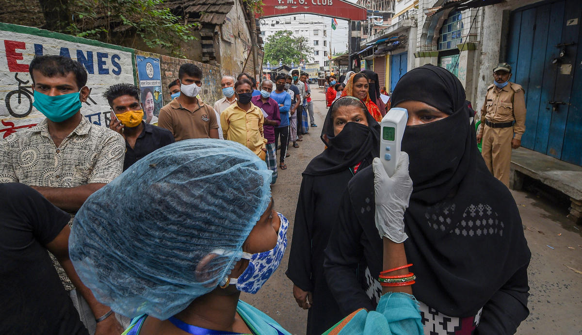 A health worker does thermal check on voters at a polling station during the 6th phase of West Bengal State Assembly Elections at Khardha, in North 24 Parganas, Thursday, April 22, 2021. Credit: PTI Photo