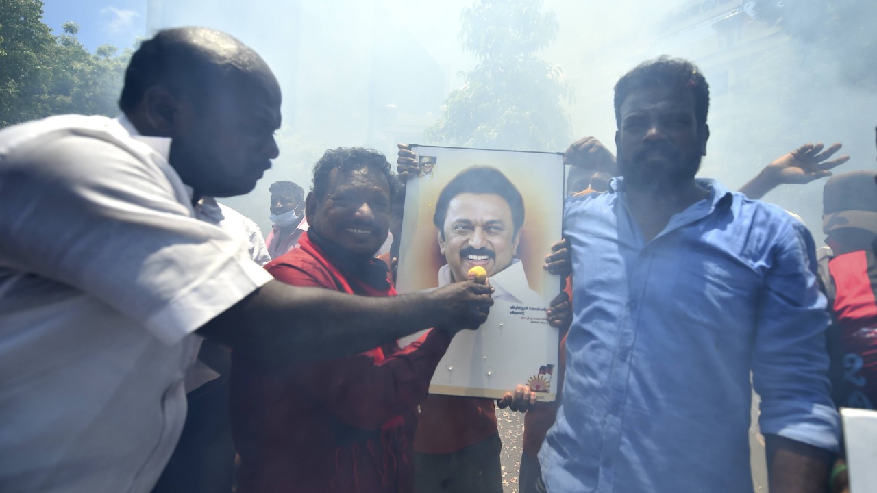 Party workers celebrate the party's performance in the Tamil Nadu elections by distributing sweets and bursting firecrackers.