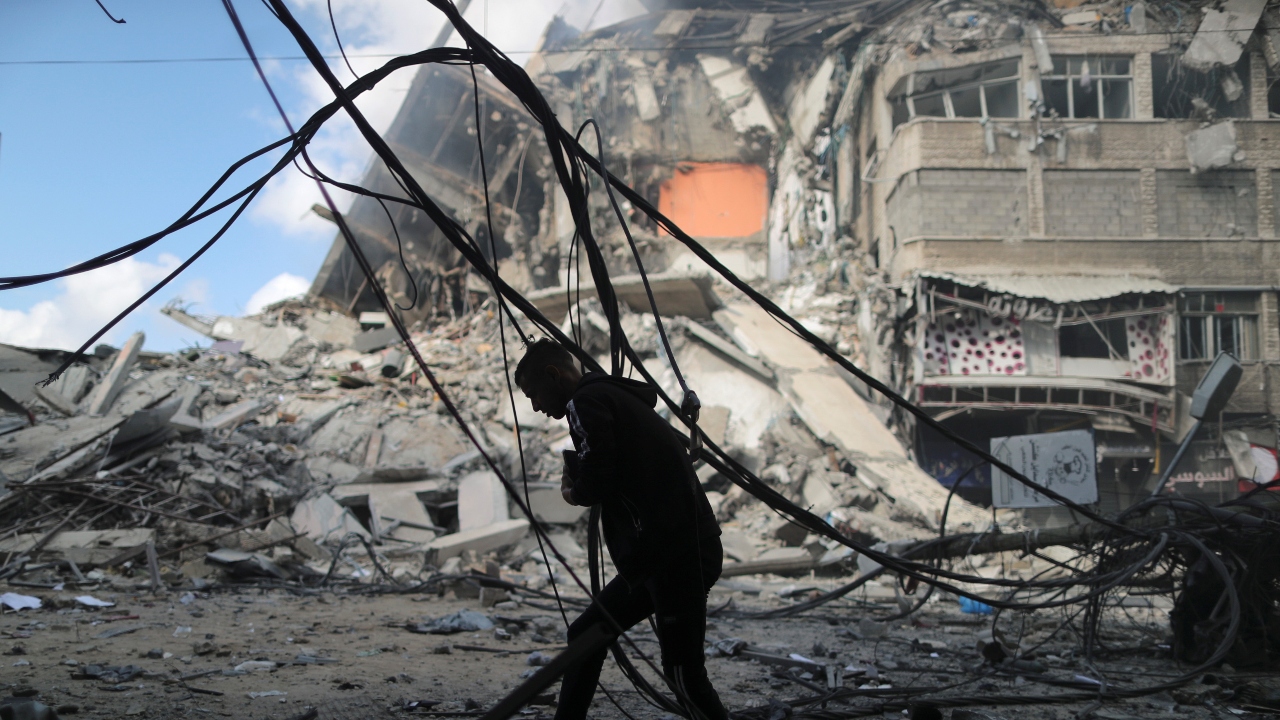 A Palestinian man runs for cover during an Israeli air strike near the ruins of a tower building which was destroyed in earlier strikes. Credit: Reuters Photo