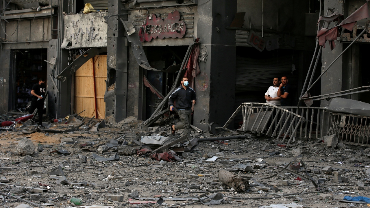 Palestinians run for cover during an Israeli air strike near the site of a tower building which was destroyed in earlier strikes, amid a flare-up of Israeli-Palestinian violence. Credit: Reuters Photo