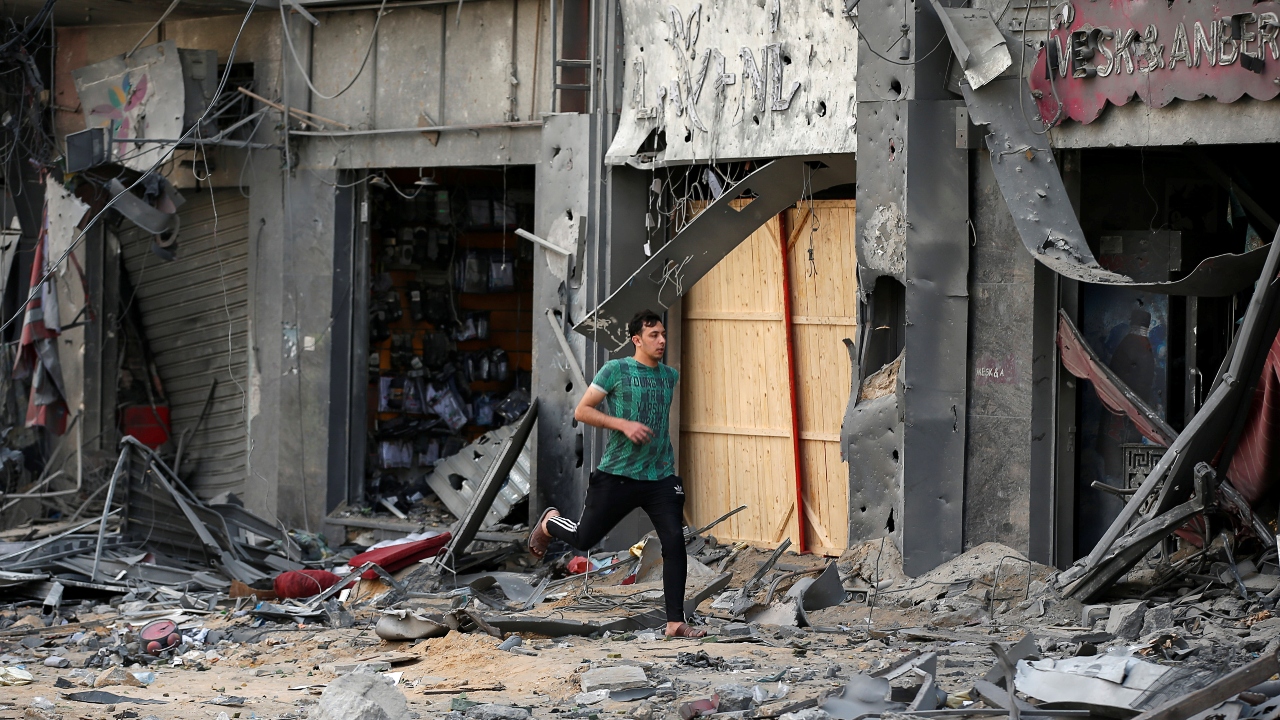 A Palestinian man runs for cover during an Israeli air strike near the site of a tower building which was destroyed in earlier strikes. Credit: Reuters Photo