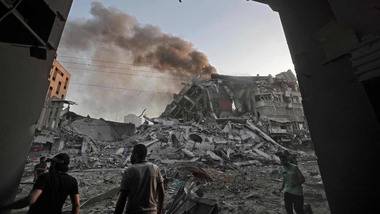 People gather amidst the rubble in front of Al-Sharouk tower that collapses after being hit by an Israeli air strike in Gaza City. Credit: AFP Photo