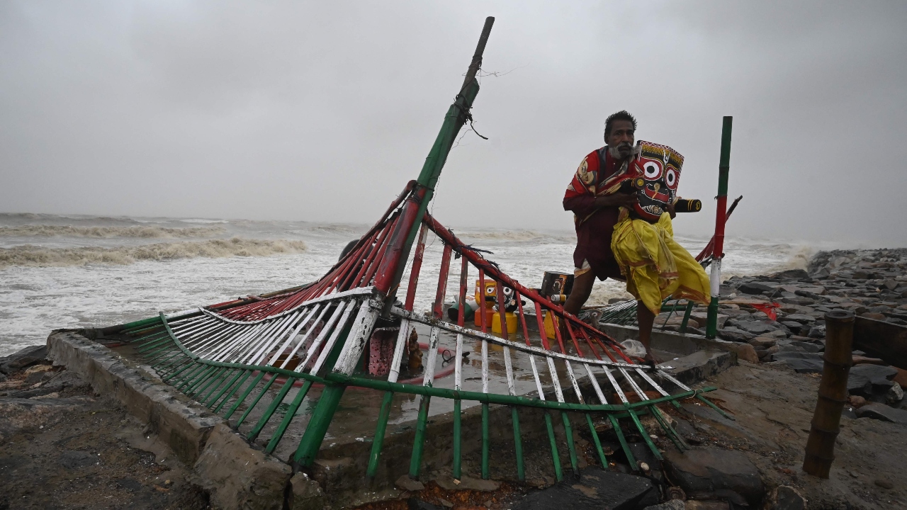 A priest removes an idol of Lord Jagannath from a seafront temple to a safer place while strong winds batter Balasore district in Odisha. Credit: AFP Photo