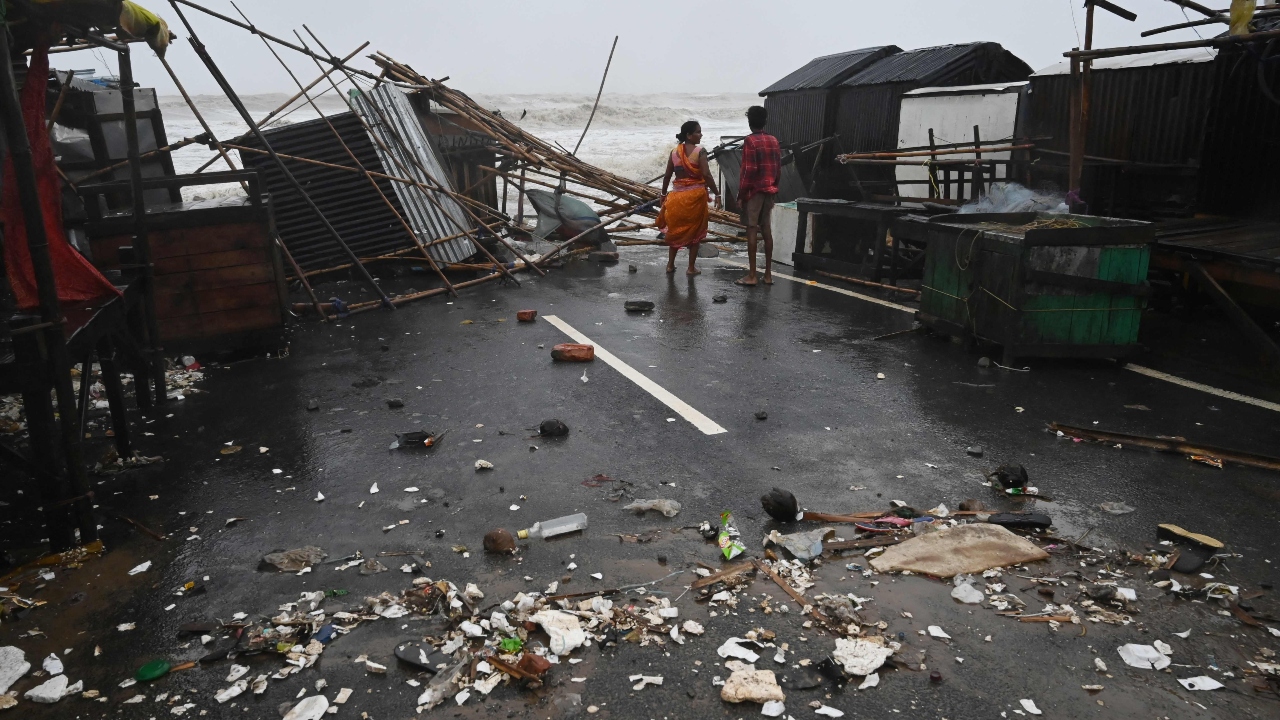 A resident walks amidst debris near stalls in a beachfront area while strong winds batter Balasore district in Odisha. Credit: AFP Photo