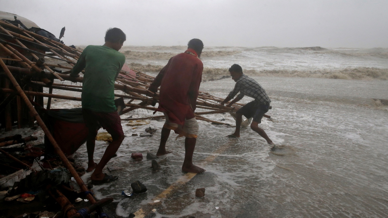 Residents shift structures of makeshifts stalls as water reaches a road at a beachfront area while strong winds batter Balasore district in Odisha. Credit: AFP Photo
