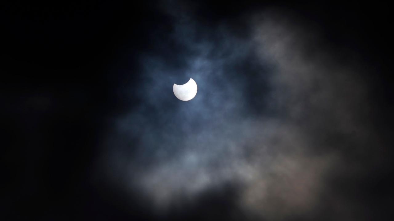 A partial solar eclipse is seen through cloud cover from Primrose Hill in central London. Credit: AFP Photo
