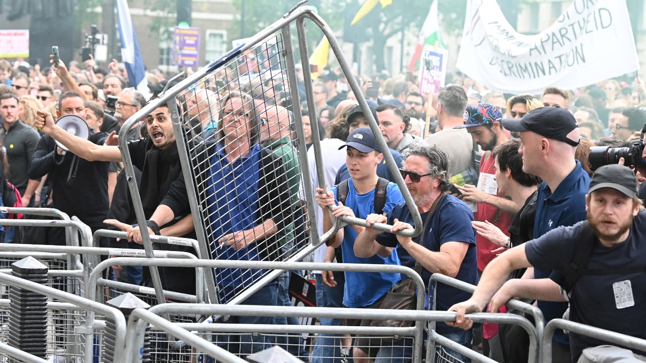 People throwing a barricade during an anti-vaccine and anti-lockdown demonstration outside Downing Street in central London.