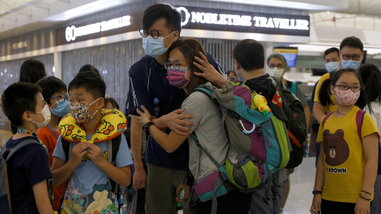 A woman reacts as she hugs a family member before departing to United Kingdom at the Hong Kong International Airport in Hong Kong, China.