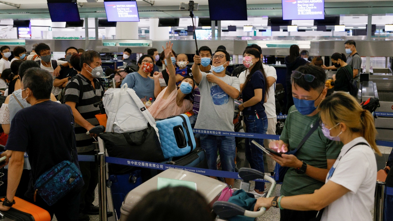 Passengers take selfies before boarding a flight to United Kingdom at the Hong Kong International Airport.