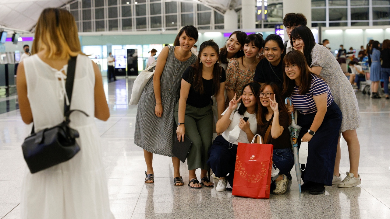 People take a group photo before their friend's departure to United Kingdom at the Hong Kong International Airport.