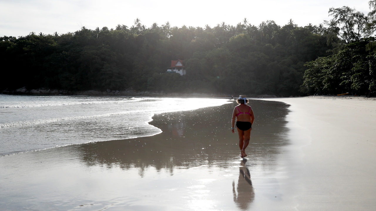 People enjoy a walk by the almost-empty Kata beach in Phuket.