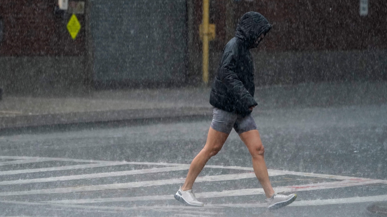 A woman walks through the rain in the Chelsea area as tropical storm Elsa moves up the Northeast with heavy rain and flash flood warnings. Credit: AFP Photo