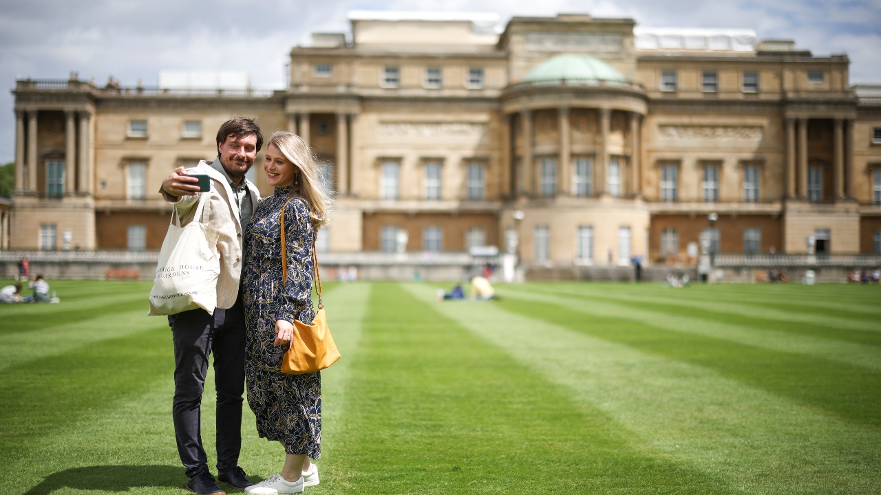 People take a selfie in the The Garden of Buckingham Palace, during a preview day before it opens to the public, in London.