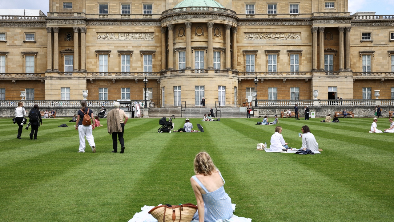 People sit together in The Garden of Buckingham Palace, during a preview day before it opens to the public, in London.