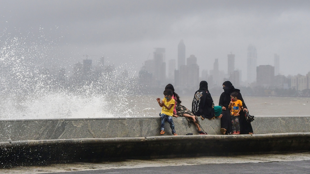 A family enjoys strong wind and tide at Marine Drive after heavy rain in Mumbai. Credit: PTI Photo