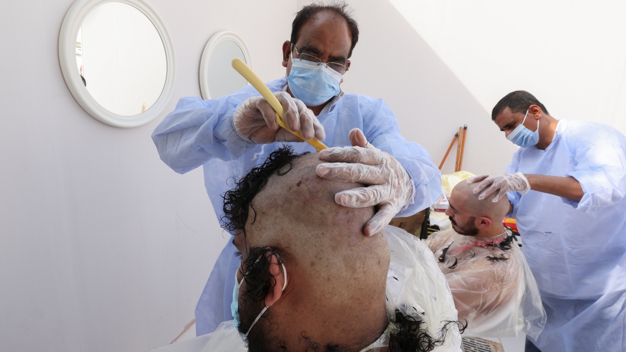 Muslim pilgrim shave their heads on the second day of Eid al-Adha, the Feast of Sacrifice, after throwing stones at a pillar symbolising Satan during the annual Hajj pilgrimage, amid the coronavirus disease (COVID-19) pandemic, in Mina, near the holy city of Mecca, Saudi Arabia. Credit: Reuters Photo