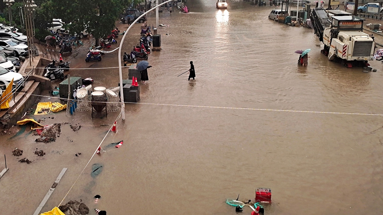 People wade through flood waters along a street following heavy rains in Zhengzhou in China. Credit: AFP Photo