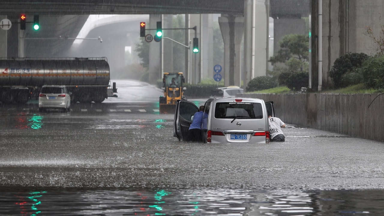 People pushing a van through flood waters along a street in Zhengzhou. Credit: AFP Photo