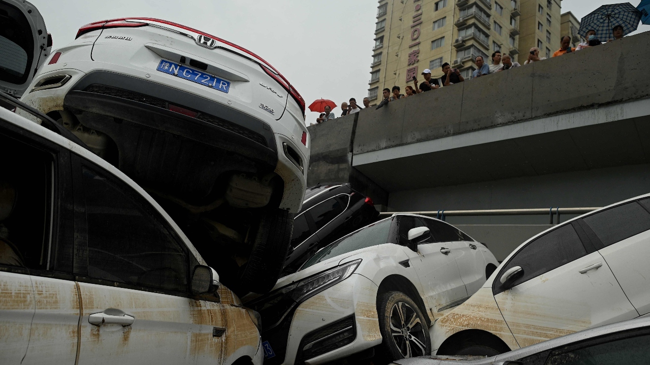 People look at cars sitting in floodwaters following heavy rains, in Zhengzhou in China. Credit: AFP Photo