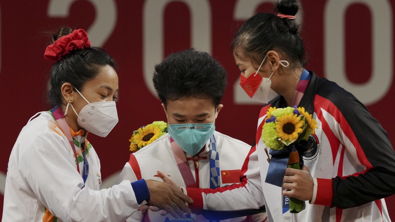 Mirabai Chanu congratulates Hou Zhihui and Aisah Windy Cantika during the presentation ceremony of women's 49 Kg category weightlifting at the Summer Olympics 2020, in Tokyo. Credit: PTI Photo